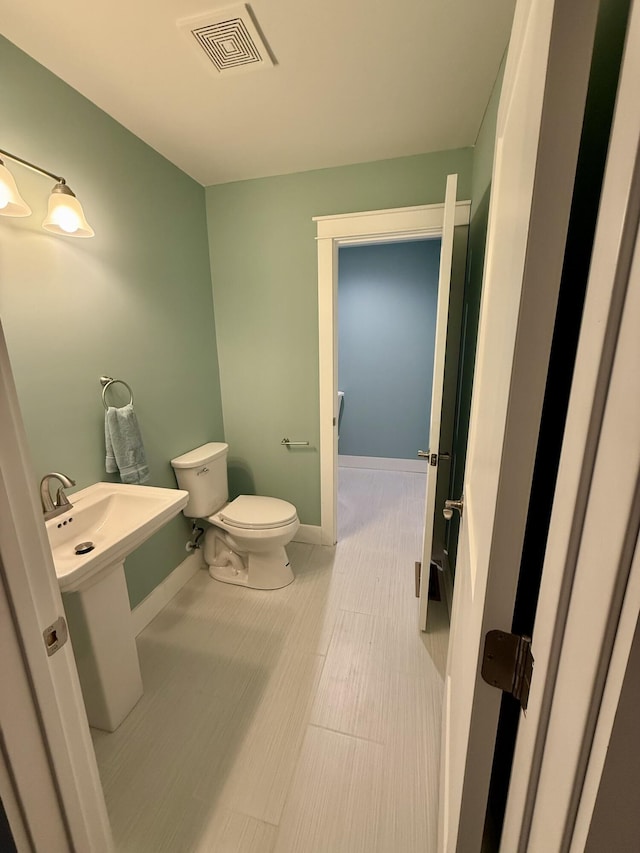 bathroom with toilet, visible vents, and baseboards