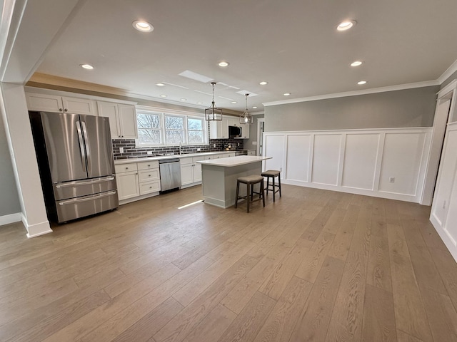 kitchen featuring stainless steel appliances, light wood-style floors, ornamental molding, and tasteful backsplash