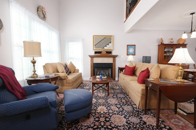 living room featuring a chandelier, a tiled fireplace, and a high ceiling