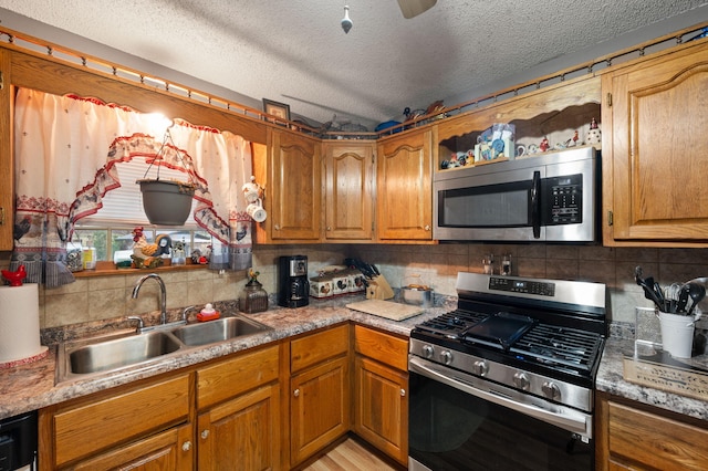 kitchen featuring tasteful backsplash, a textured ceiling, stainless steel appliances, and a sink