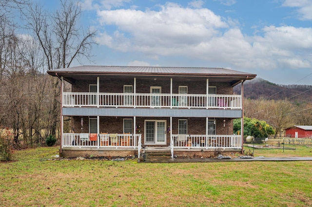 view of front facade with brick siding, a balcony, a front yard, and covered porch