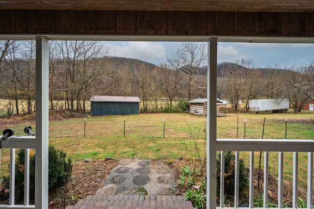 view of yard featuring a mountain view, an outbuilding, a shed, and fence