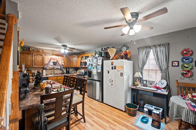 kitchen with brown cabinetry, a ceiling fan, a textured ceiling, and appliances with stainless steel finishes