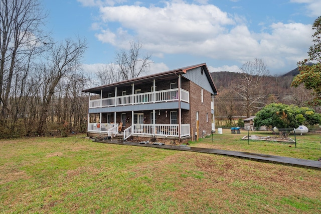back of house with a porch, a lawn, brick siding, and a balcony