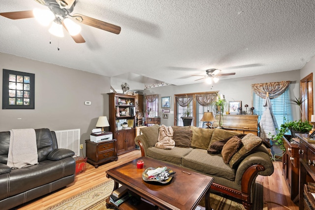 living area featuring plenty of natural light, ceiling fan, visible vents, and light wood-style flooring