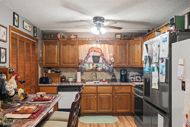 kitchen featuring stainless steel appliances, a ceiling fan, a sink, and brown cabinetry