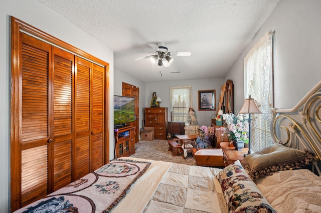 carpeted bedroom with a textured ceiling, a closet, and ceiling fan