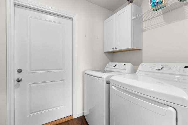 laundry area featuring dark wood finished floors, washing machine and dryer, and cabinet space