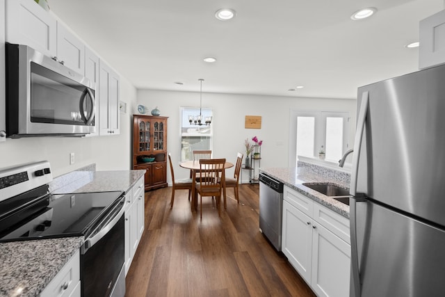 kitchen with stainless steel appliances, light stone counters, decorative light fixtures, and white cabinets