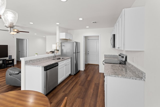 kitchen with light stone counters, dark wood-style flooring, a sink, white cabinets, and appliances with stainless steel finishes