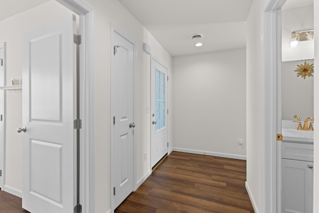 hall with recessed lighting, a sink, visible vents, baseboards, and dark wood finished floors