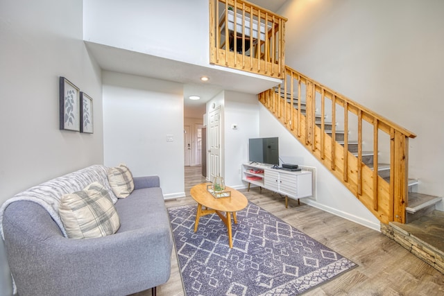 living room with baseboards, stairs, a towering ceiling, and wood finished floors