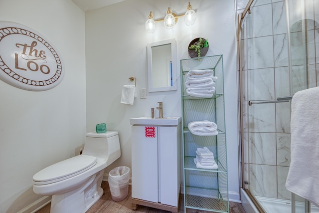 bathroom with tiled shower, toilet, vanity, and baseboards