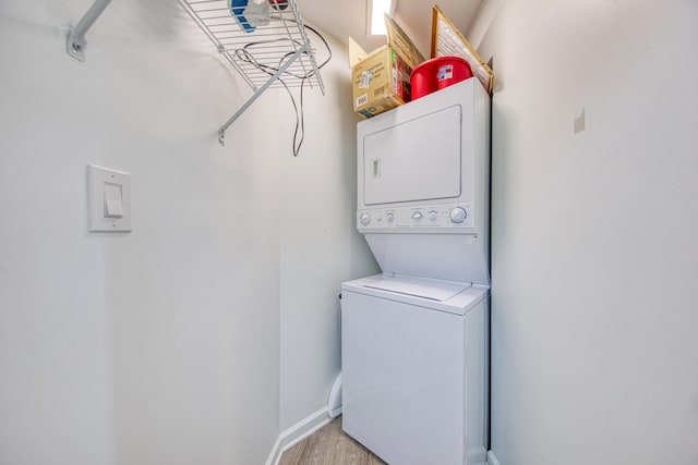 washroom with laundry area, stacked washer / dryer, light wood-style floors, and baseboards