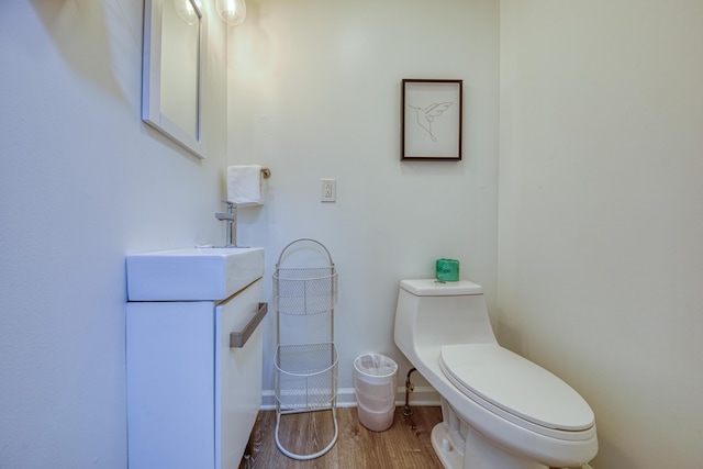 bathroom with vanity, toilet, wood finished floors, and baseboards