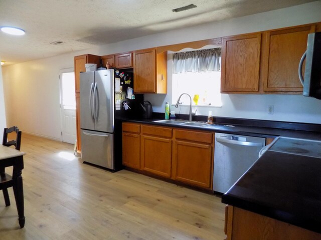 kitchen featuring a healthy amount of sunlight, sink, light hardwood / wood-style floors, and appliances with stainless steel finishes