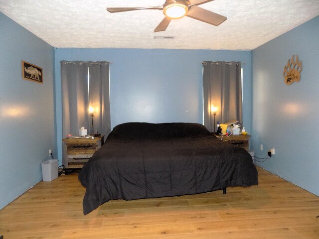 bedroom with a textured ceiling, light hardwood / wood-style floors, and ceiling fan