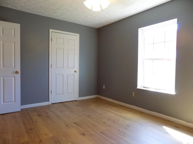 unfurnished bedroom with light wood-type flooring and a textured ceiling