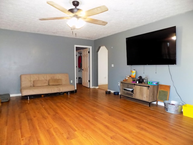 living room featuring hardwood / wood-style floors, a textured ceiling, and ceiling fan