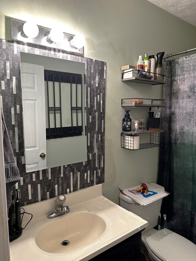 bathroom with vanity, toilet, and a textured ceiling