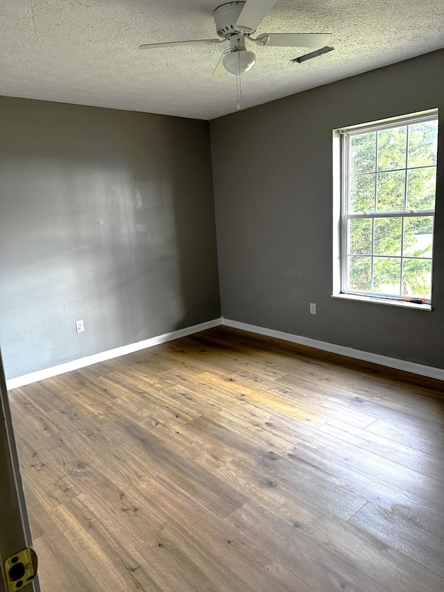 empty room featuring ceiling fan, hardwood / wood-style floors, and a textured ceiling