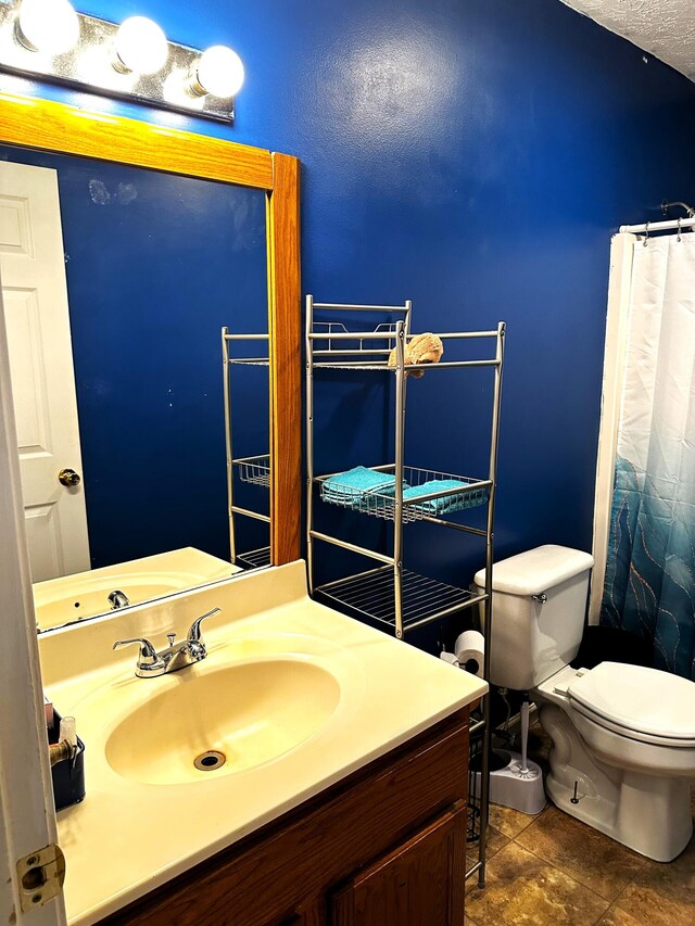 bathroom featuring tile patterned flooring, vanity, a textured ceiling, and toilet