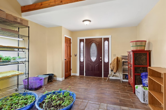 entrance foyer with wood finish floors, beam ceiling, and baseboards