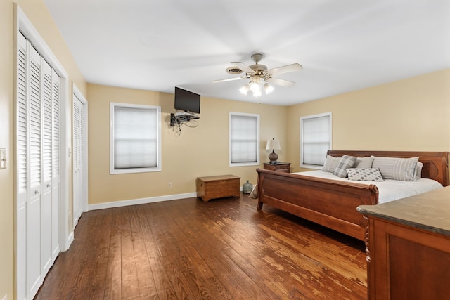 bedroom with multiple closets, dark wood-style flooring, ceiling fan, and baseboards