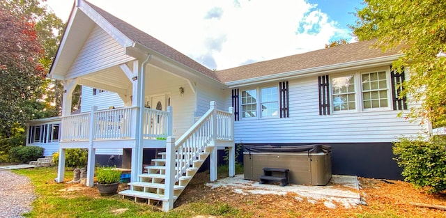 exterior space featuring a hot tub, stairs, and a shingled roof