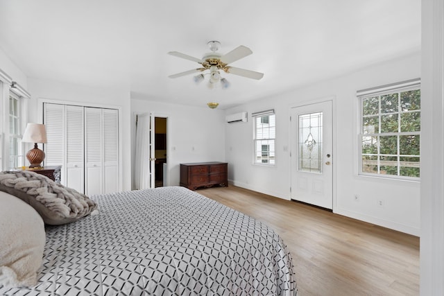 bedroom with a ceiling fan, baseboards, wood finished floors, and a wall mounted air conditioner