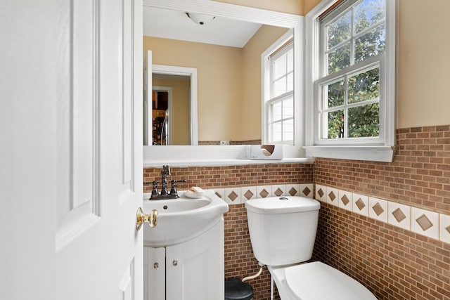 bathroom with tile walls, a wainscoted wall, vanity, and toilet