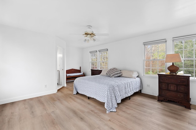 bedroom featuring ceiling fan, light wood-style flooring, and baseboards