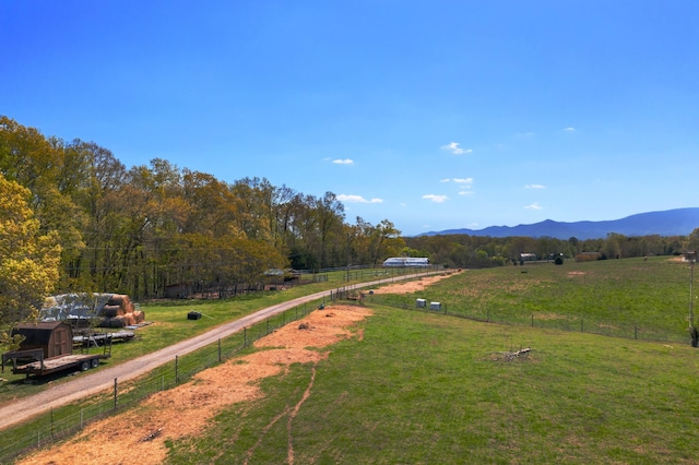 view of property's community featuring a yard, a rural view, fence, and a mountain view