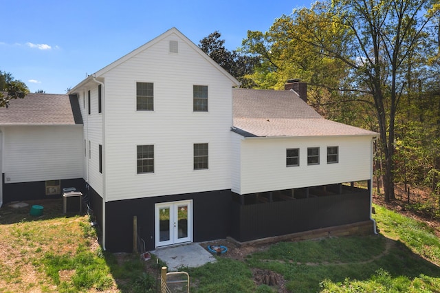 rear view of house featuring cooling unit, french doors, roof with shingles, and a chimney