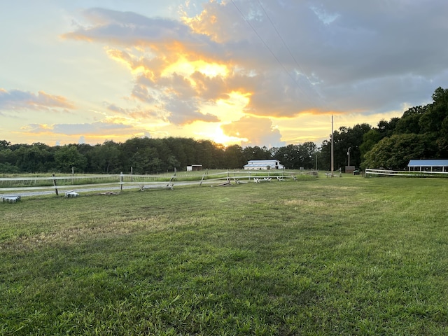 yard at dusk featuring a rural view