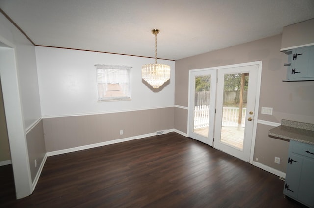 unfurnished dining area featuring dark wood-type flooring and an inviting chandelier