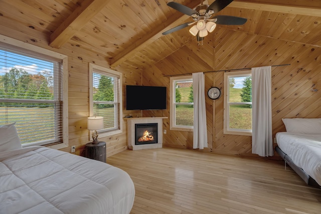 bedroom with wooden walls, light hardwood / wood-style flooring, ceiling fan, beam ceiling, and wood ceiling