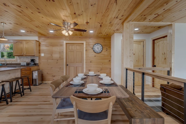 dining area with ceiling fan, wood walls, light wood-type flooring, and wooden ceiling