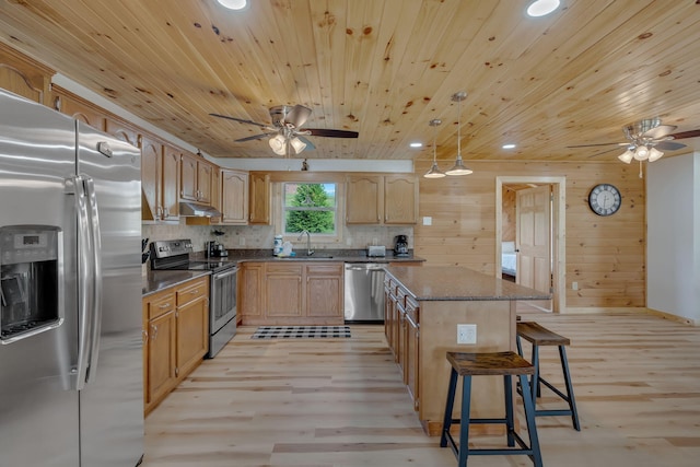 kitchen featuring hanging light fixtures, sink, light wood-type flooring, appliances with stainless steel finishes, and a kitchen island