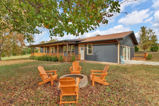 back of house featuring a lawn, a porch, and an outdoor fire pit