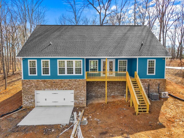 rear view of property featuring a garage and central AC