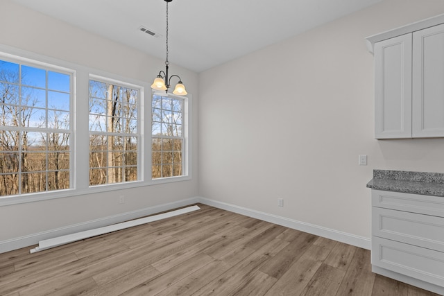 unfurnished dining area with baseboards, visible vents, an inviting chandelier, and light wood-type flooring