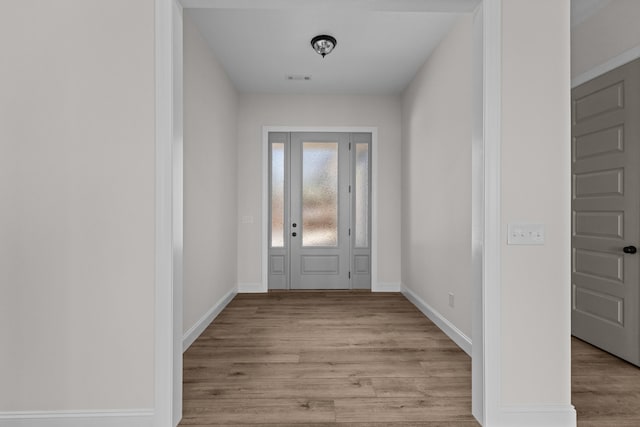 foyer entrance with baseboards, visible vents, and wood finished floors