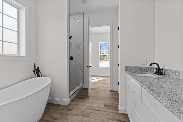 bathroom featuring a soaking tub, a marble finish shower, baseboards, and wood finished floors