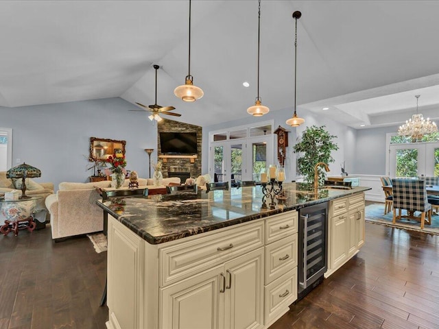 kitchen with dark stone countertops, hanging light fixtures, beverage cooler, and cream cabinets