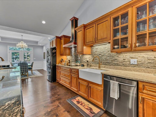 kitchen with light stone countertops, refrigerator, stainless steel dishwasher, sink, and decorative light fixtures