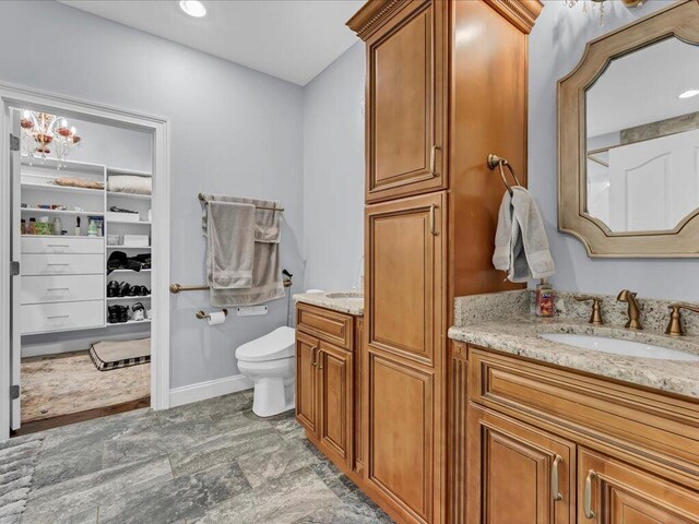 bathroom with a notable chandelier, vanity, and toilet