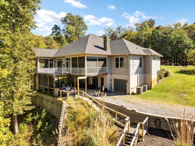 back of property with a patio area, a sunroom, cooling unit, and a garage