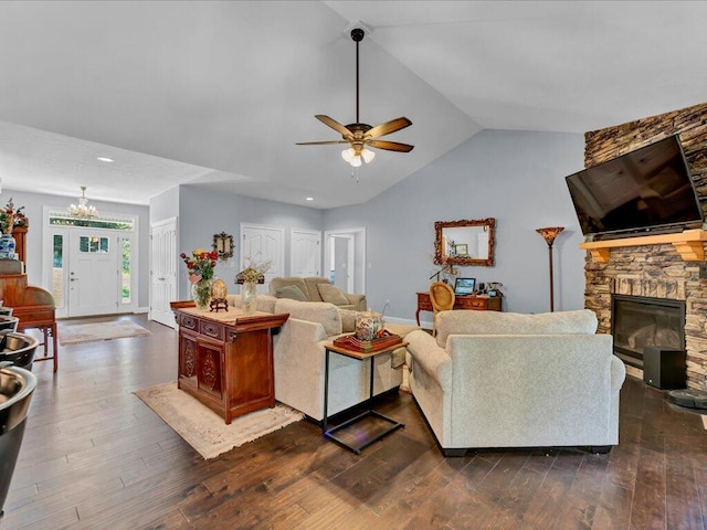 living room featuring vaulted ceiling, a fireplace, dark wood-type flooring, and ceiling fan with notable chandelier