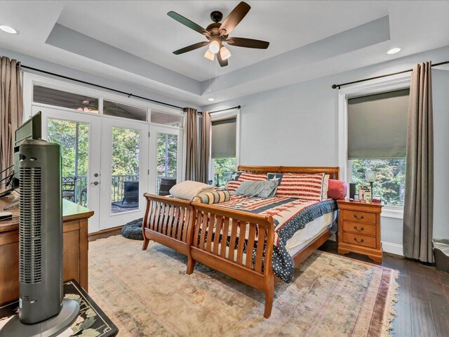 bedroom featuring ceiling fan, dark hardwood / wood-style floors, french doors, and a tray ceiling